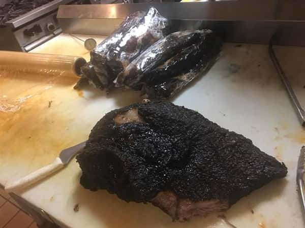 Blackened brisket resting on the kitchen counter next to a big kitchen knife