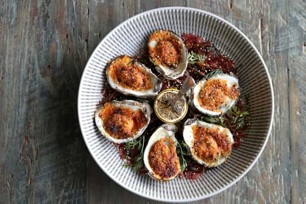 Ostiones Asados, roasted oysters with toppings served on a platter, a fresh seafood dish at Zaranda Houston