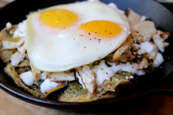 Chilaquiles with sunny-side-up eggs, salsa and toppings, a classic Mexican breakfast dish at Zaranda Houston