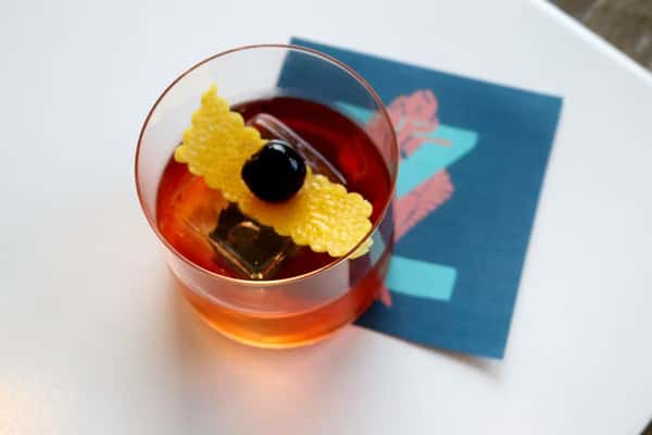Old Fashioned cocktail with orange peel and dark cherry, served in a crystal glass, part of the craft cocktail menu at Zaranda Houston