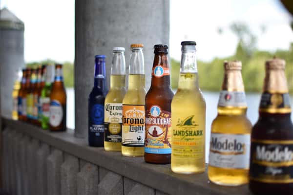 assortment of beer bottles lined up on railing outside