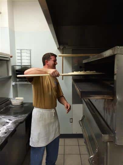 Worker Making Pizza by Putting it in the Oven