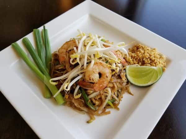 grilled shrimp over noodles with chives and garnish