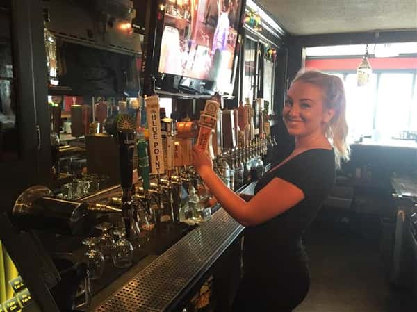 waitress smiling as shes pouring a beer from the tap