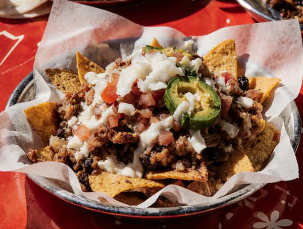 Loaded nachos topped with seasoned meat, pico de gallo, jalapeño slices, and melted cheese on crispy tortilla chips.