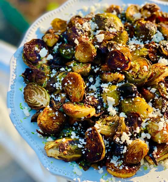 Roasted Brussels sprouts with crumbled cheese on a serving platter