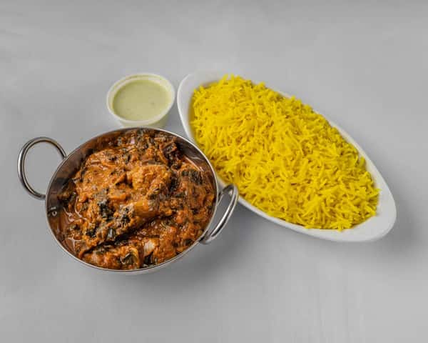 A bowl of Indian food beside a bowl of rice