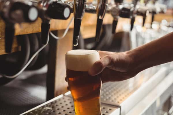 Bartender filling up a glass with beer from a tap