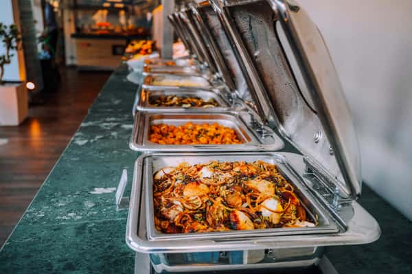 buffet station with hot trays of pasta and mixed dishes in a self-serve restaurant setup