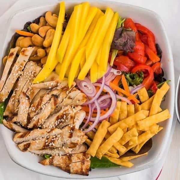 salad topped with grilled chicken, onions, and vegetables