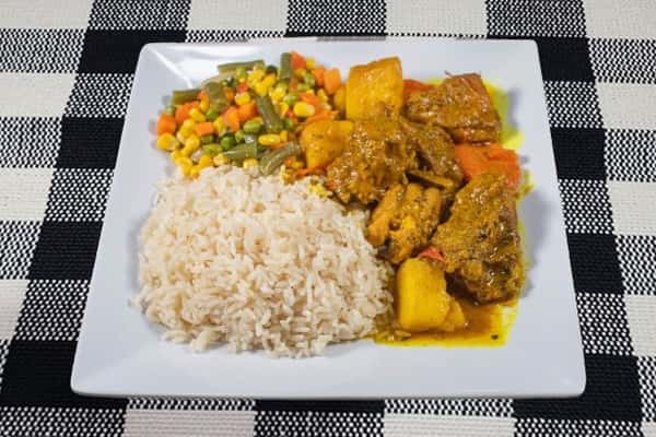 Chicken curry served with a side of vegetables and rice