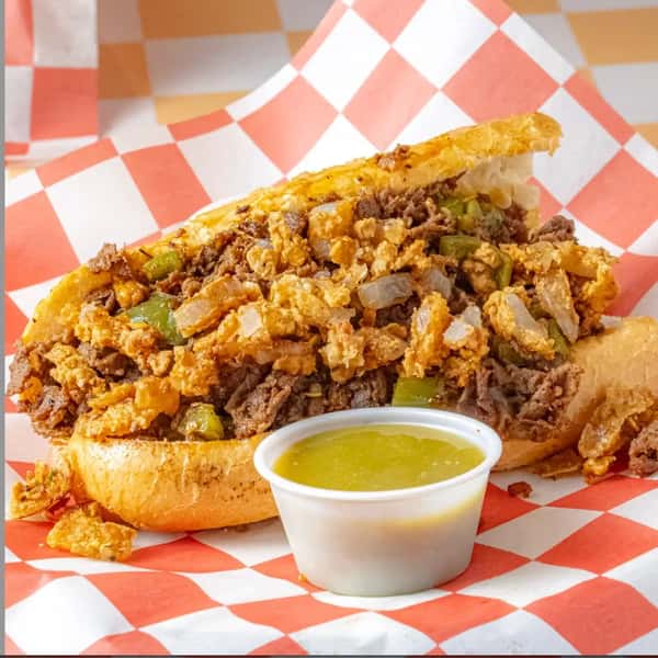 spicy cheesesteak sandwich topped with chopped peppers and melted cheese served with dipping sauce