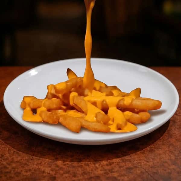 crispy fries topped with warm melted cheese sauce being poured over the top