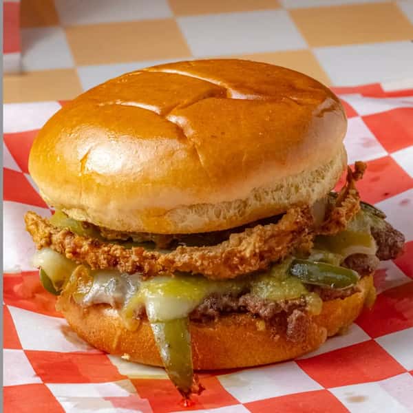 spicy smash burger with melted cheese, peppers, and sauce on a toasted bun