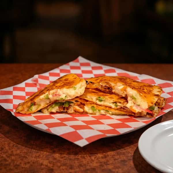 grilled quesadilla filled with crispy fried chicken and melted cheese on a checkered tray