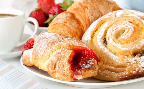 Assortement of breakfast pastries on a plate with a cup of coffee