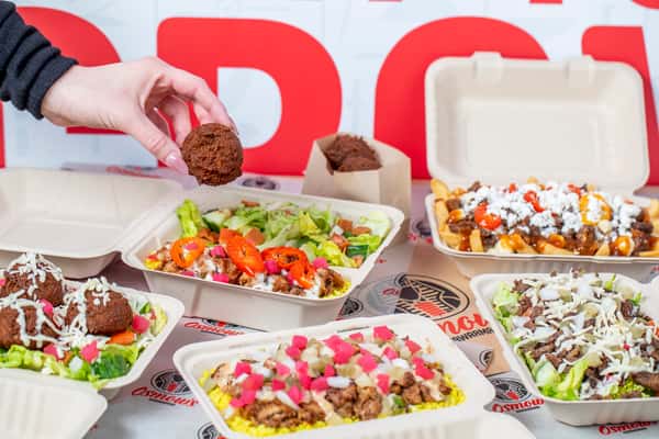 Hand grabbing a falafel from a container of food