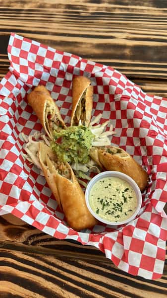 Crispy fried egg rolls filled with meat and vegetables, served with guacamole, cabbage slaw, and creamy dipping sauce.