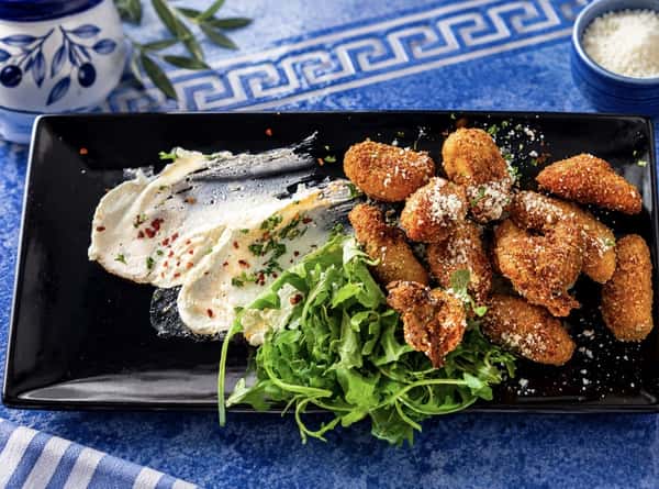 An appetizer with fresh greens and dip