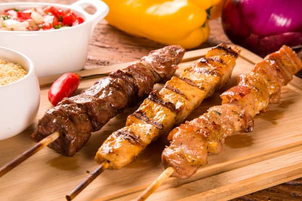 Beef, chicken and lamb kabobs on a wooden tray