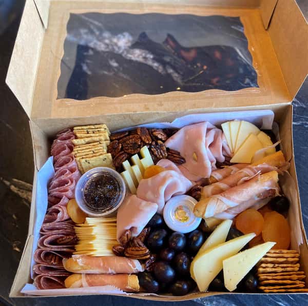 charcuterie box with meats, cheese, crackers, and fruit