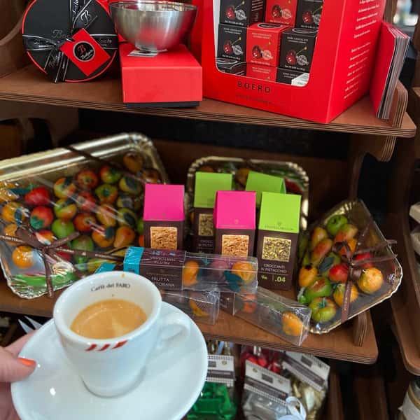person holding a cup of coffee in front of a shelf with products