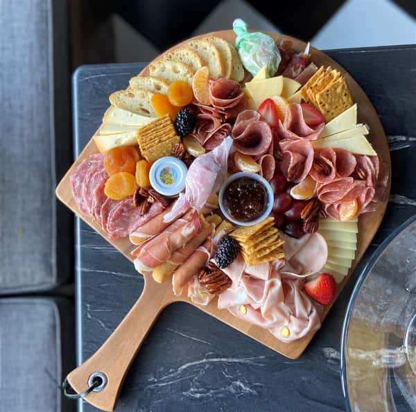 charcuterie board with meats, cheese, crackers, and fruit