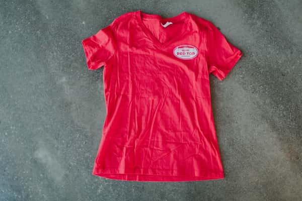 Women's cut red tee with small white oval logo on upper left