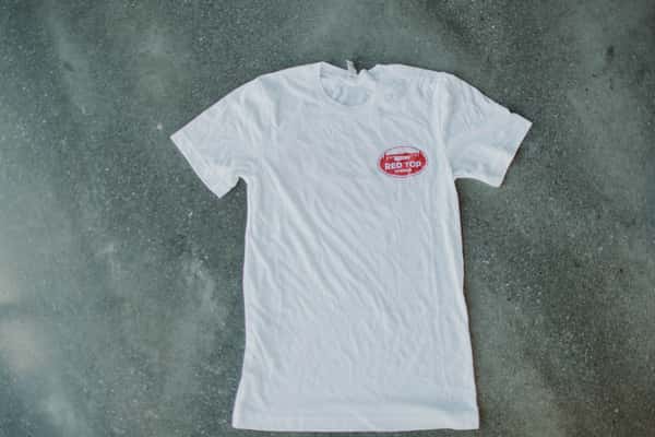 White tee with small oval logo on upper left.