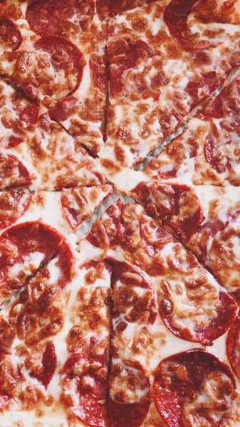 Overhead view of pepperoni pizza with generous mozzarella cheese, featuring perfectly crisped edges and evenly spaced slices.