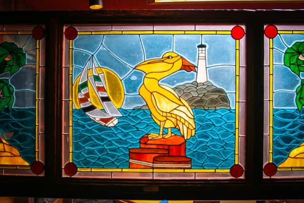 Stained glass of yellow Seagull with a lighthouse in the background