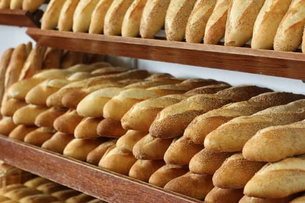 Italian bread piled on top of each other on wooden shelves
