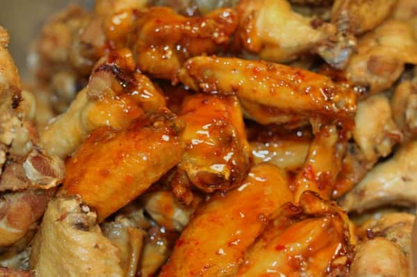 A pile of chicken wings topped with sauce
