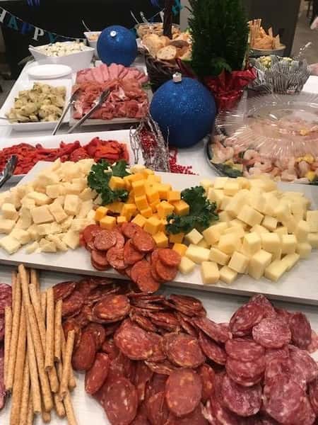 A tray of cubes cheeses and sliced meats on a buffet table