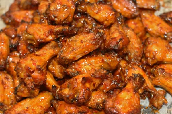A pile of chicken wings topped with sauce