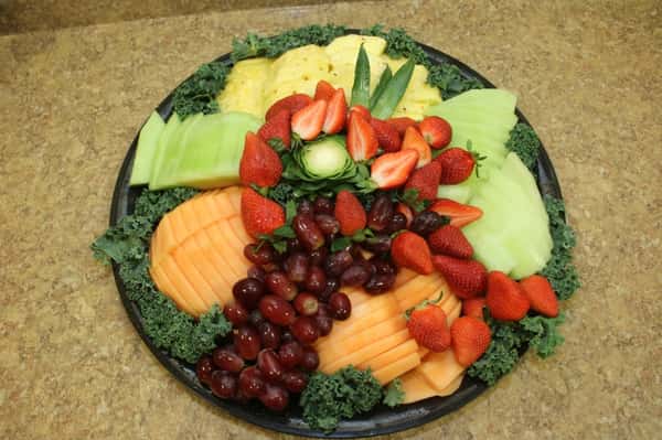 A fruit platter with fruit such as pineapple, cantaloupe, strawberries, and grapes.