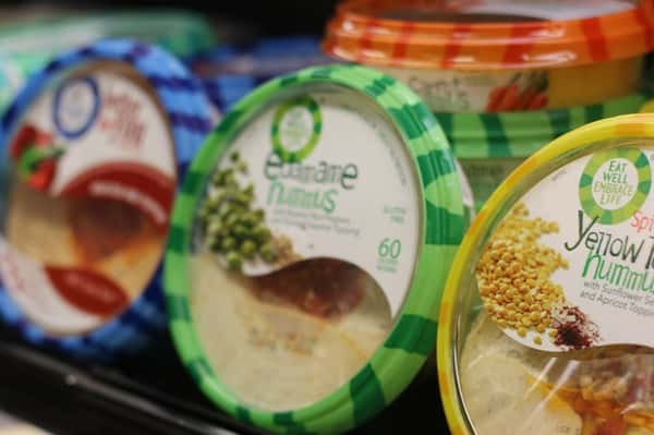 A shelf with containers of different flavors of hummus