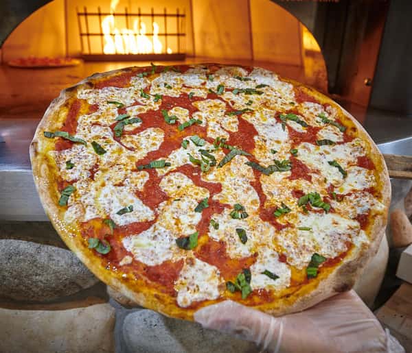 Chef taking a cheese pizza out of the oven