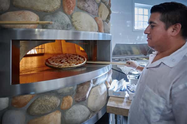 Chef taking a pizza out of the oven