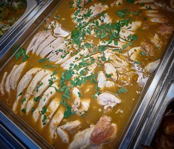 Assortment of sliced meat covered in gravy topped with garnish
