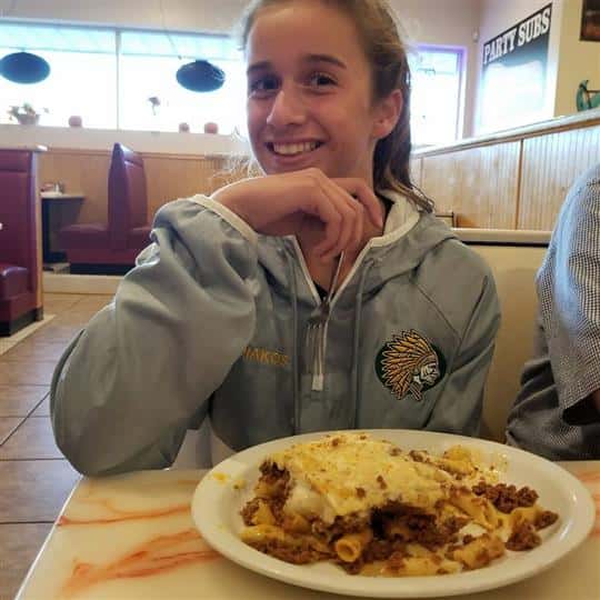 female smiling with entree on table