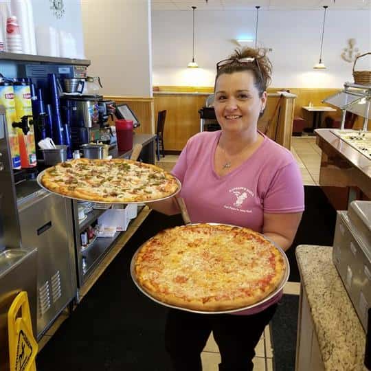 female employee holding two pizza pies