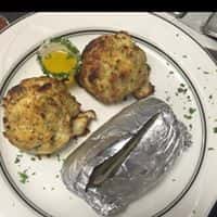 two crab cakes and a baked potato