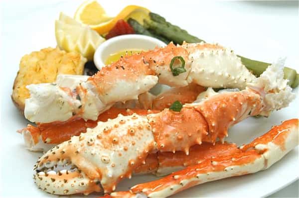 Crab legs with a side of steamed vegetables and a side of melted butter