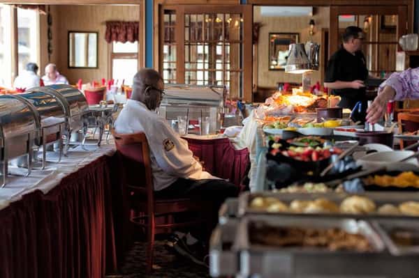 Chef at buffet table sitting next to assortment of food