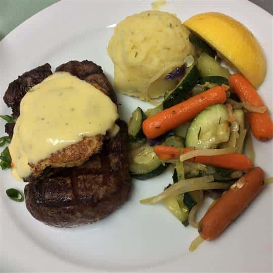Grilled steak topped with Bearnaise sauce and a side of steamed vegetables and mashed potatoes