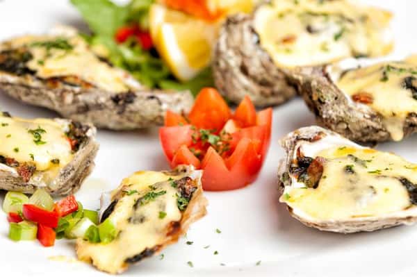 Tomato cut into the shape of rose cut surrounded by oysters with hollandaise sauce
