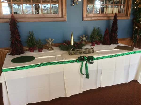 Table set-up with small fake Christmas trees decorated with a green ribbon
