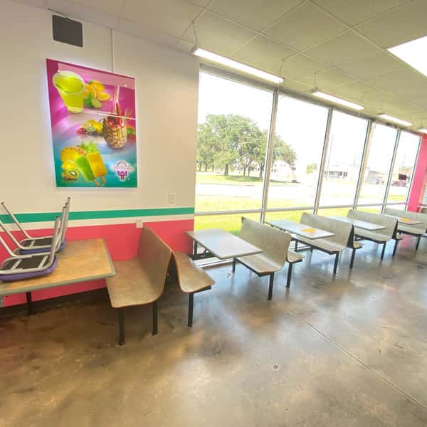 A brightly lit interior of "La Michoacana Autentica" with tables, chairs, and a colorful poster on the wall showcasing fruit and frozen treats.
