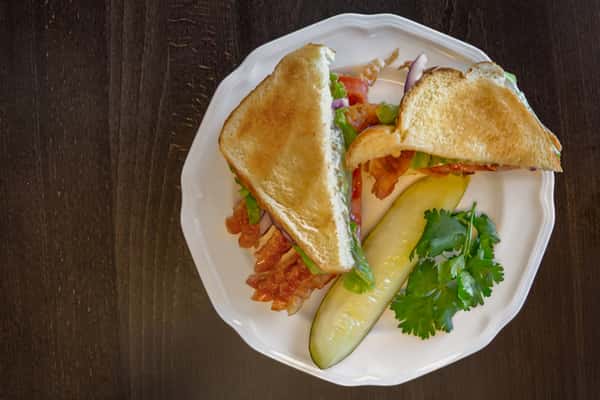Classic BLT sandwich with crispy bacon, lettuce, and tomato on toasted white bread, served with a pickle. Add a side of chips, a side salad, or a fruit cup for an additional cost.